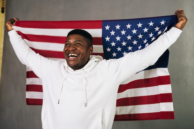 man holding american flag behind head