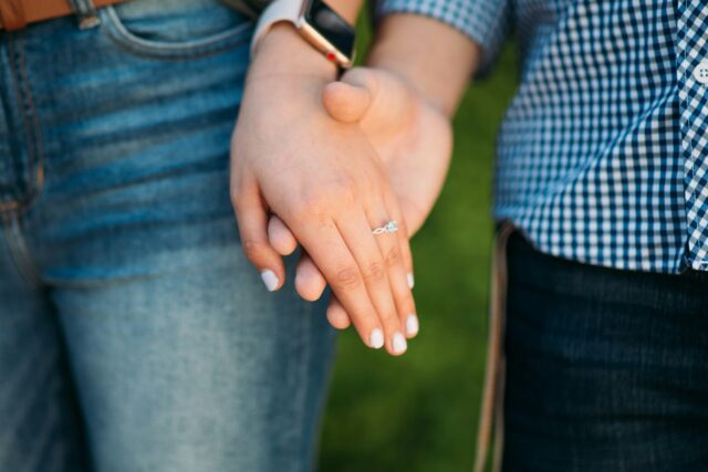 couple holding hands to show engagement ring