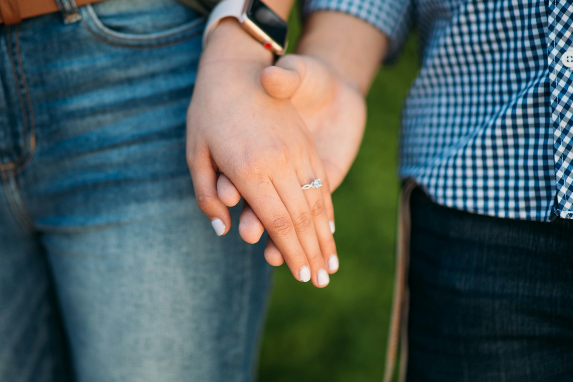 couple holding hands to show engagement ring image