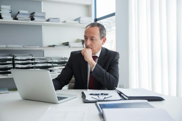 man looking at computer next to documents