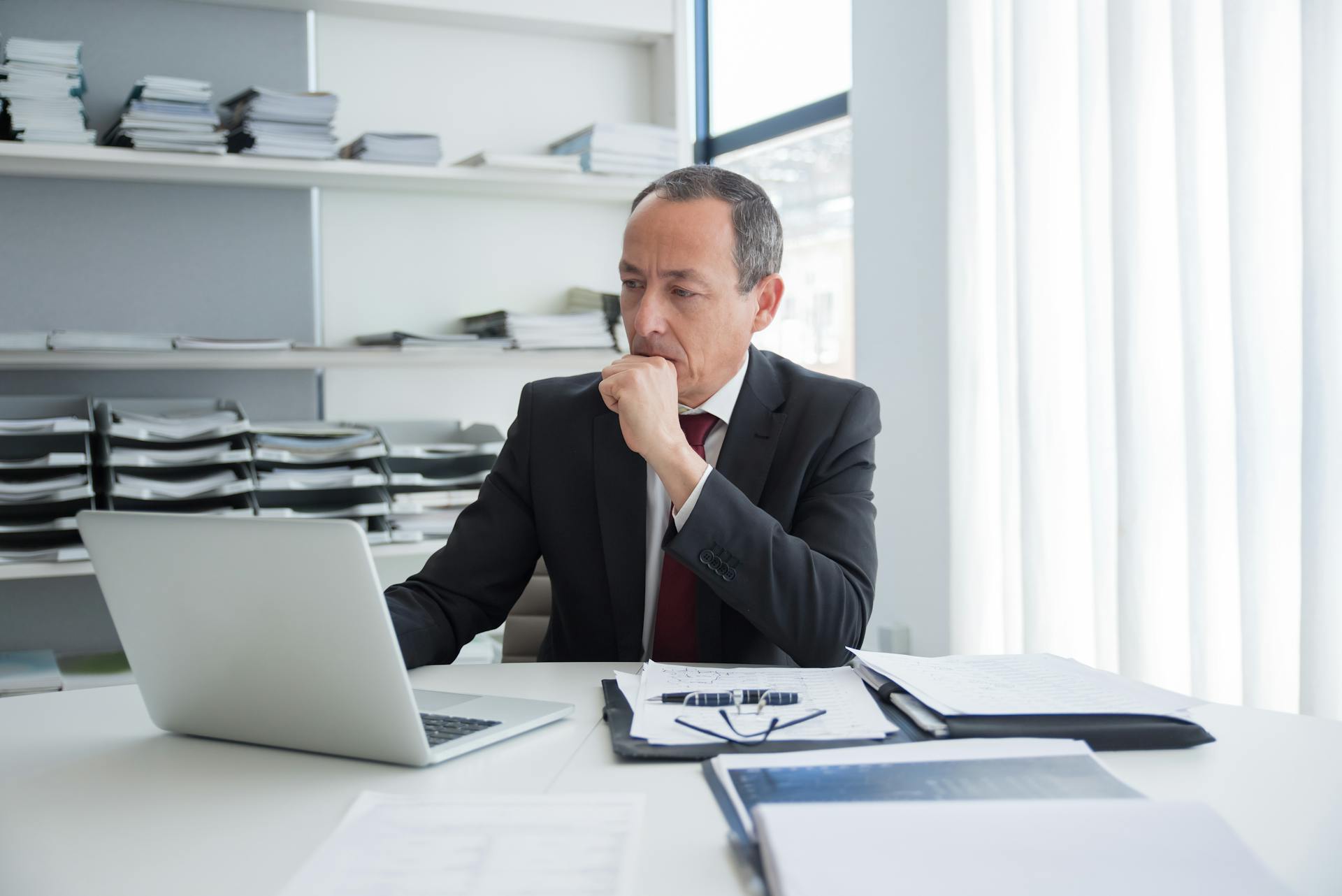 man looking at computer next to documents image