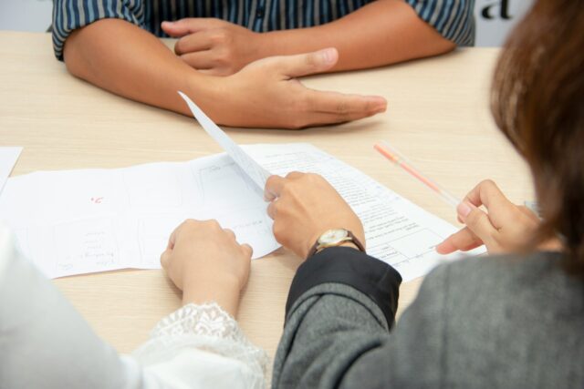 man sitting across from people with papers